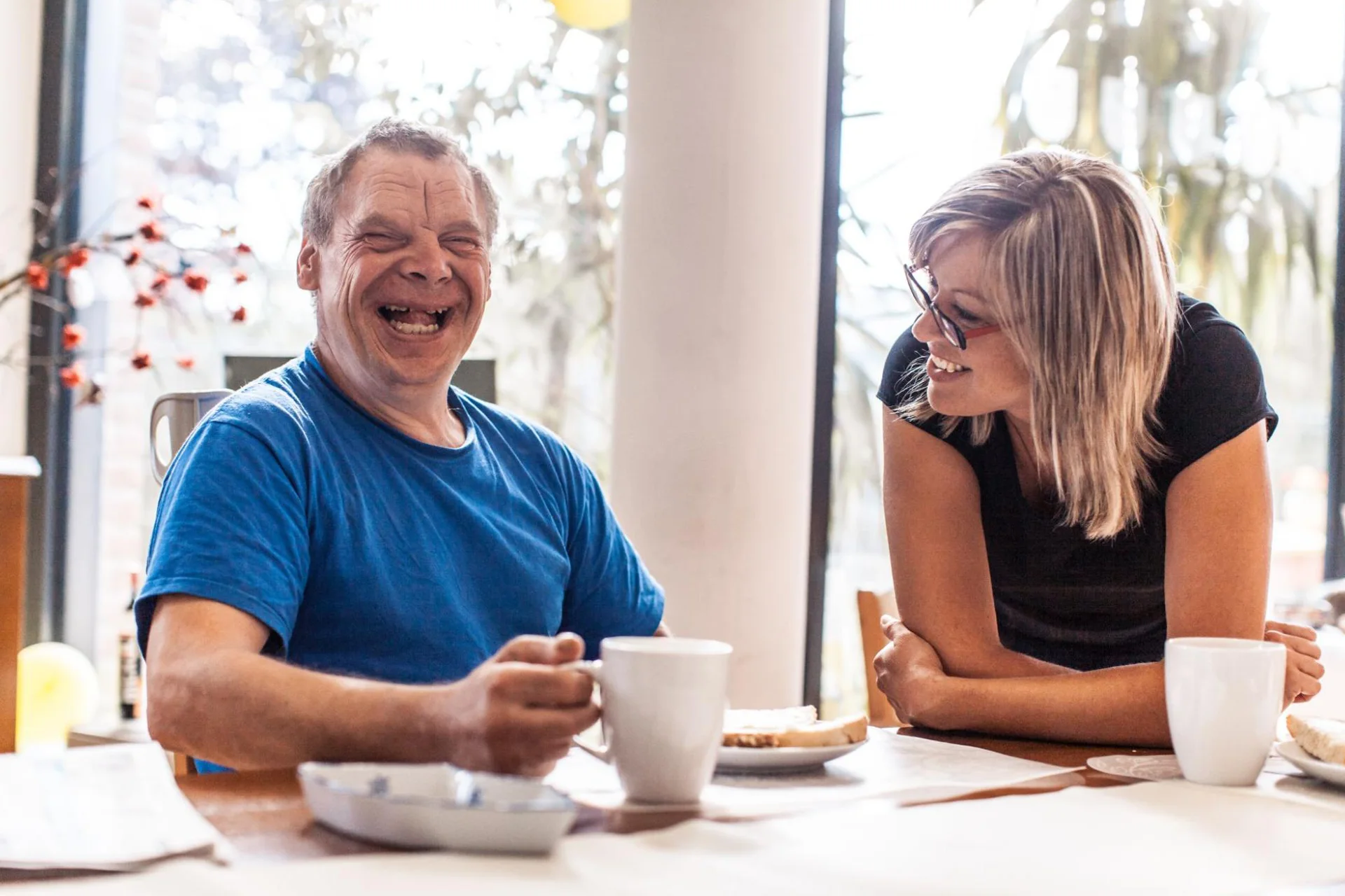 Man holding cup laughing with support worker