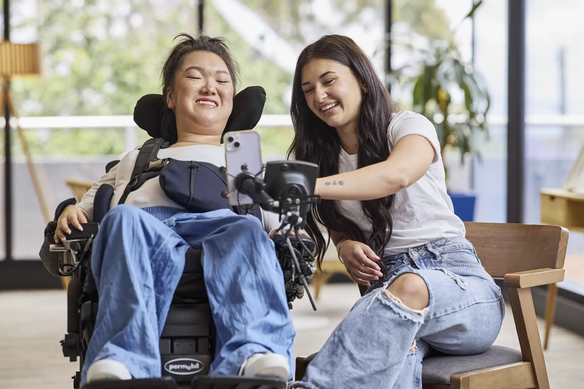 Support worker showing how to use mobile to a disabled lady